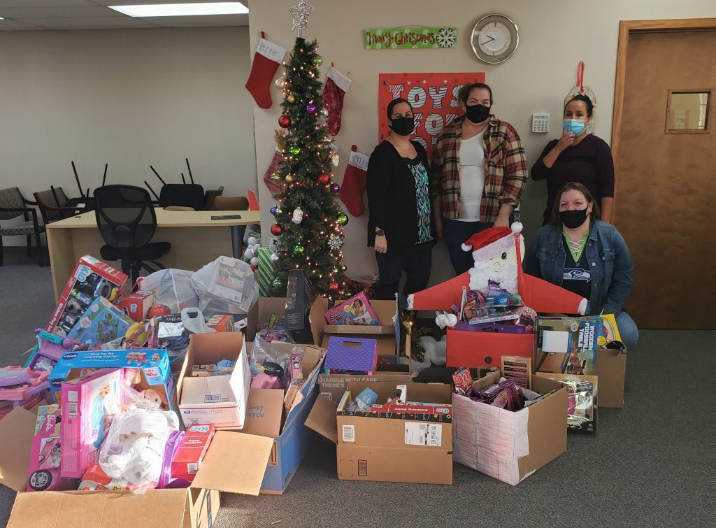group of happy people in office with toys for tots donations