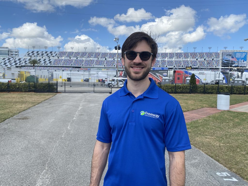 Race car driver Daniel Suarez wearing Freeway shirt standing outside of race track stadium