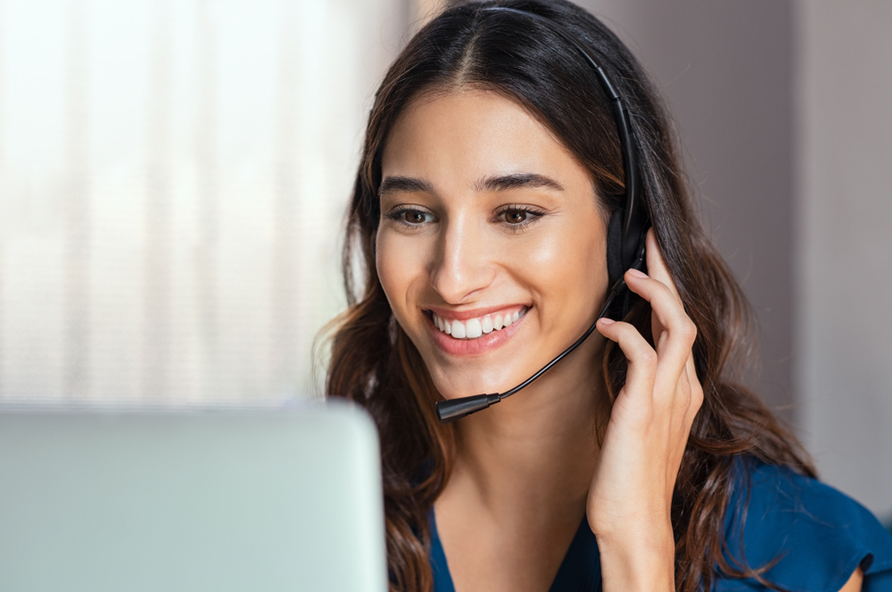 Smiling young woman talks to a customer in a call center customer service