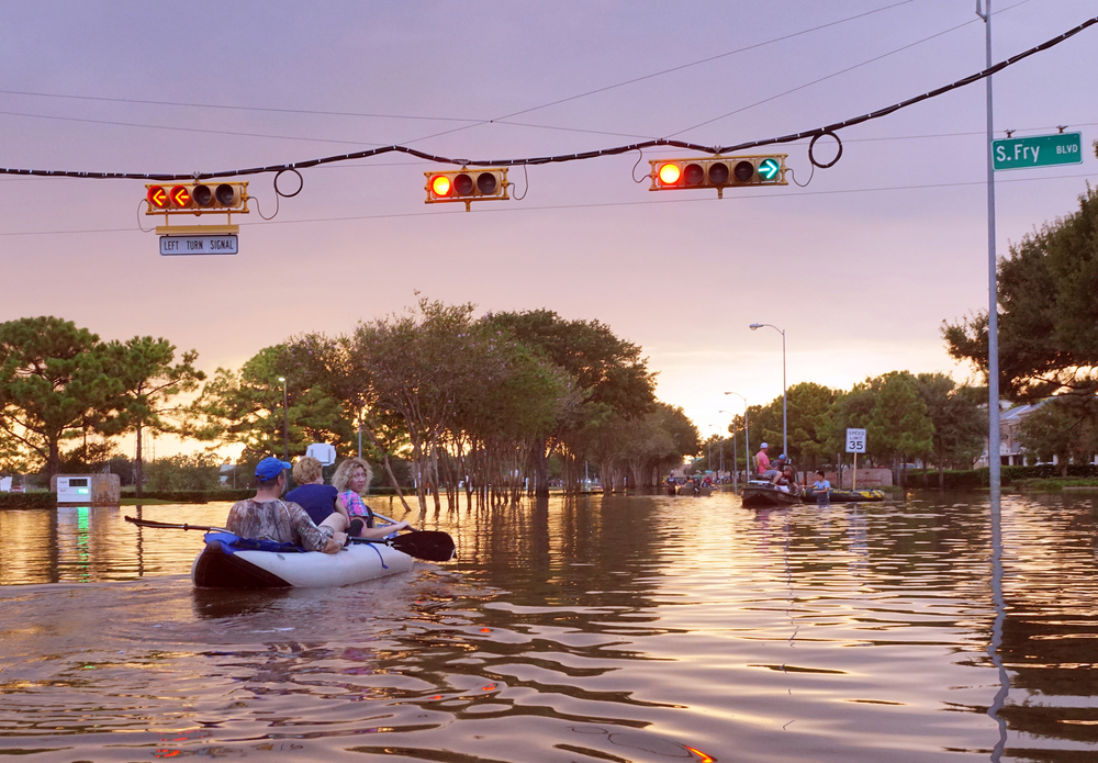 Canoe with people navigates through flooded street